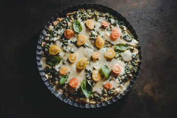 homemade tart pie with spinach, fresh tomatoes and basil leaves