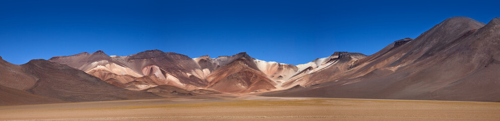 Fototapeta na wymiar Panorama of The colourful Andes mountain range in the Salvador Dali Desert (Desierto de Salvador Dali) in the Altiplano region of Bolivia. 