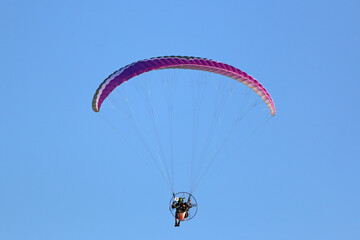Paramotor pilot flying in a blue sky	