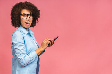 Portrait of her she nice attractive lovely cheerful african american black girl holding in hands mobile phone chatting on web isolated over pink background.