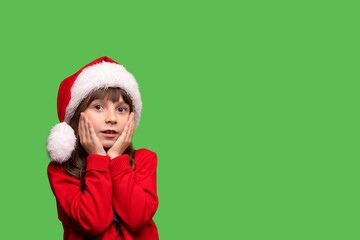 Merry Christmas and New Year. Portrait of a surprised girl in a red Santa hat waiting for Christmas gifts.