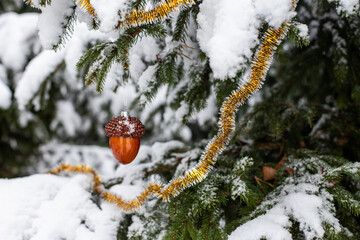 Christmas decoration on the tree under the snow. Christmas toy on the tree. Christmas big acorn