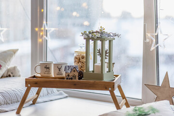 Morning Christmas coffee with marshmallows and Christmas decorations on a tray table by the window on the windowsill