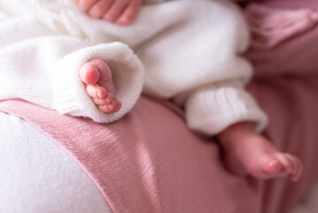 A close up of a content and peaceful newborn baby's bare feet. The baby is being cuddled by her mother.