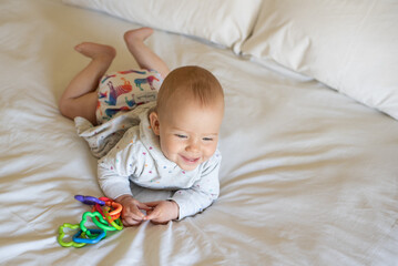 A happy, content baby lying on her stomach doing tummy time to strengthen her back. She is wearing a modern, reusable cloth diaper