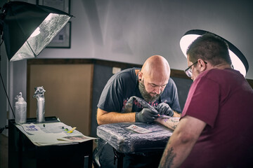 Tattoo Artist tätowiert Kunden im Studio am Tisch