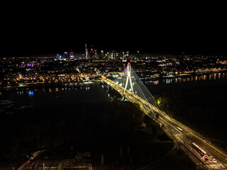Fototapeta na wymiar The Swietokrzyski Bridge over Vistula river, on modern cable-stayed bridge in Warsaw, Downtown. Aerial night view
