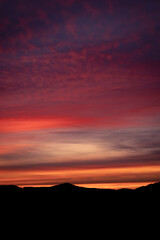 Silhouettes of mountains, red, colorful winter sunset sky in Germany, Europe 