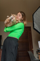 Portrait of a young beautiful blonde girl with a cat in her arms in a home studio.