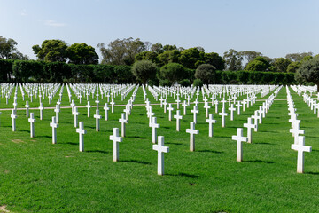 Fototapeta na wymiar North Africa American Cemetery, honoring the victims of World War 2. White tombstones and green maintained fields. Memorial and remembrance of fighters. 