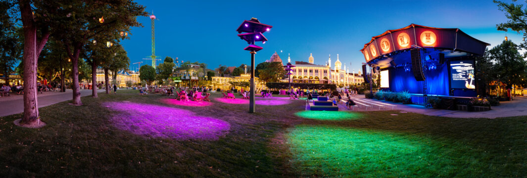Copenhagen, Denmark. Circa August 2022.Panorama of magical Tivoli Gardens at night with rides, shows and performances. Popular amusement park very important tourist attraction