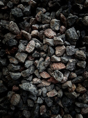 Isolated close up many crushed stone ground floor background. Selective focus center granite gravel texture with dark colors