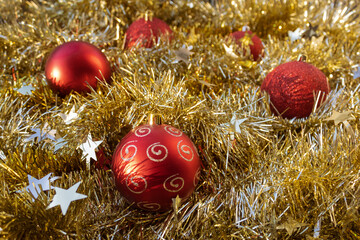 Red Christmas balls on shiny gold tinsel 