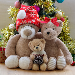 Teddy bear family (two parents and one child) portrait in front of decorated Christmas tree   