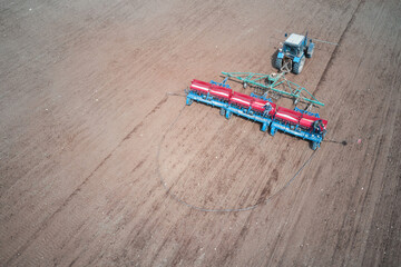 Tractor with a seeder in the field. Seeds and complex mineral fertilizer are in the seeder bunkers....