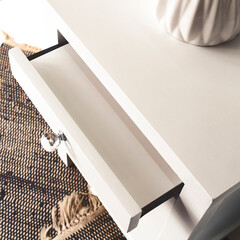 High angle view of a white drawer part of a white bed table isolated in a bedroom next to a white wall