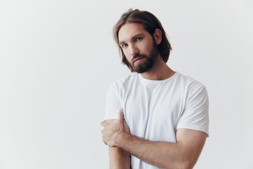 Portrait of a man with a black thick beard and long hair in a white T-shirt on a white isolated background