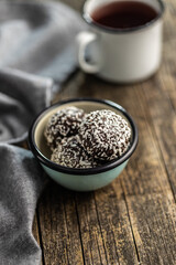 Coconut chocolate balls in bowl on wooden table.