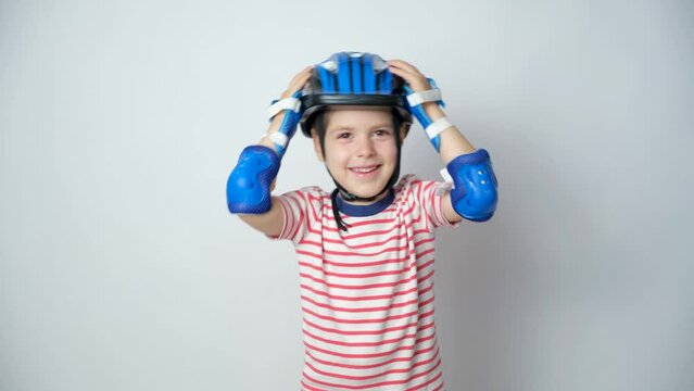 A Happy Boy In A Protective Helmet, Elbow Pads And Gloves On A White Background Is Having Fun