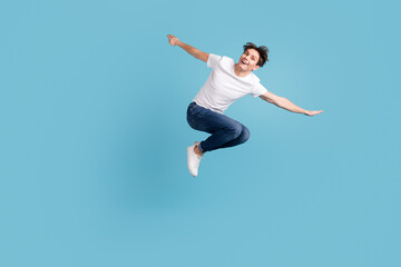 Fototapeta na wymiar Full size photo of young happy excited smiling positive man jumping isolated on blue color background