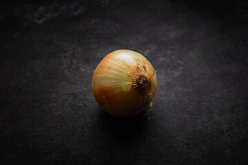 Onions with peeling skin, on dark concrete