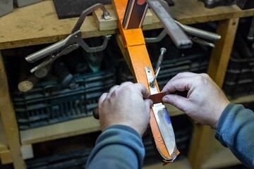 The knife maker shapes and sharpens the newly constructed blade. Production process engineering...