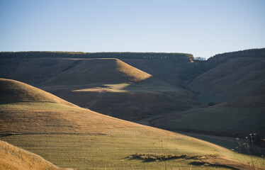 Mountain hills and slopes with a valley and yellowed grass in autumn, in sunny weather in the mountains