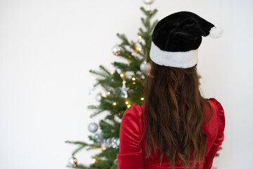 Nahaufnahme von einer Frau von hinten, mit langen braunen Haaren und einer roten Weihnachtsmütze,...