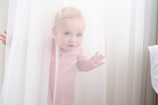 baby playing and hiding with white curtains