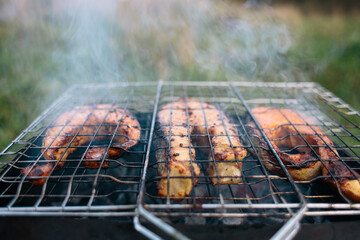 Red fish is grilled on the grill. There is smoke.