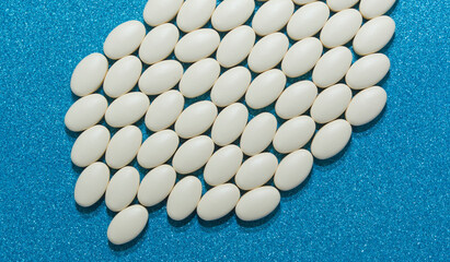 Large tablets of white color on a blue shiny background. A medicinal product.