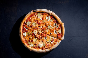 Appetizing pizza with hunting sausages, mozzarella cheese, pickled cucumbers, chili peppers on a tomato base. Mexican pizza. Top view