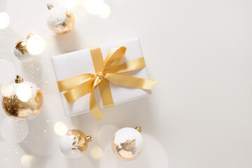 Beautiful Christmas gift, white and golden decorative balls, bokeh on white background. Xmas greeting card with copy space. Modern luxury Christmas card. Happy New Year.