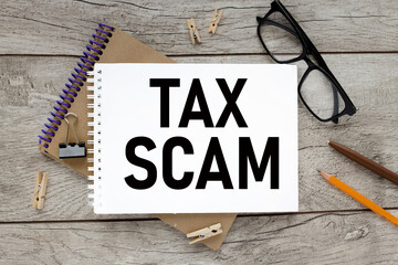tax scam, text on wooden background on paper
