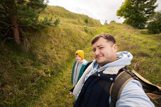 Father with son making selfie with backpack at forest.