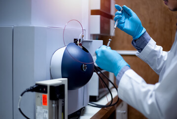 Scientist inject sample with micro syringe to TOF Mass Spectrometer for analysis in laboratory.