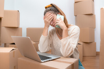 Caucasian woman with headache from moving to new home with laptop and talks to consultant on phone. High quality photo