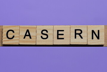 word casern made from wooden gray letters lies on a lilac background
