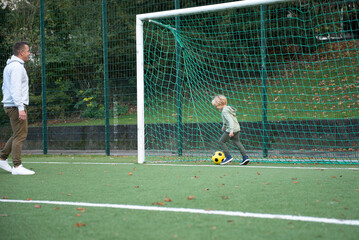 a little boy plays soccer with his father on the soccer field