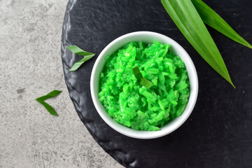 Tape Ketan Ijo Hijau Green Glutinous Tape on tinwal, made from steamed glutinous rice which is given the aroma and color from pandan leaves. Served on bowl with pandan leaves