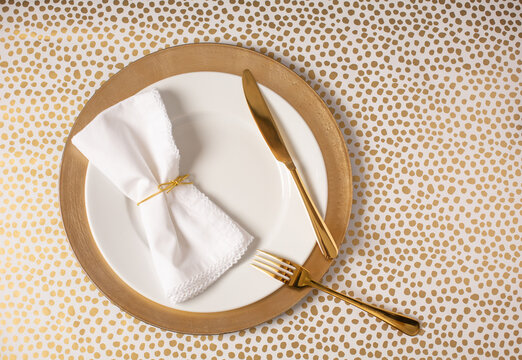 White Plate On Gold Charger With Gold Silverware