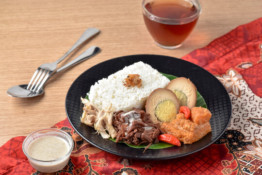 Gudeg is a traditional dish from Yogyakarta, Indonesia. Made from young unripe jack fruit. Served with rice, krecek, telur bacem, and shreded chicken. Served on plate with tea