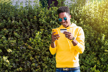 Young man holding paying card and mobile