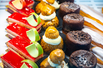 Assortment of french fresh baked sweet pastry with fresh fruits and berries in confectionery shop