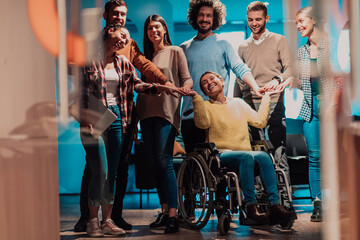 Businesswoman in a wheelchair on break in a modern office with her team in the background