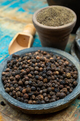 Indian spices collection, dried black peppercorns and another spices in clay bowls