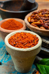 Colorful ground spicy chili peppers , pimento and curcuma is clay pots close up