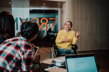 Businesswoman in wheelchair having business meeting with team at modern office. A group of young...