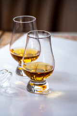 Tasting of whiskey, tulip-shaped tasting glasses with dram of Scotch single malt or blended whisky on white table