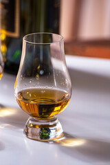 Tasting of whiskey, tulip-shaped tasting glasses with dram of Scotch single malt or blended whisky on white table
